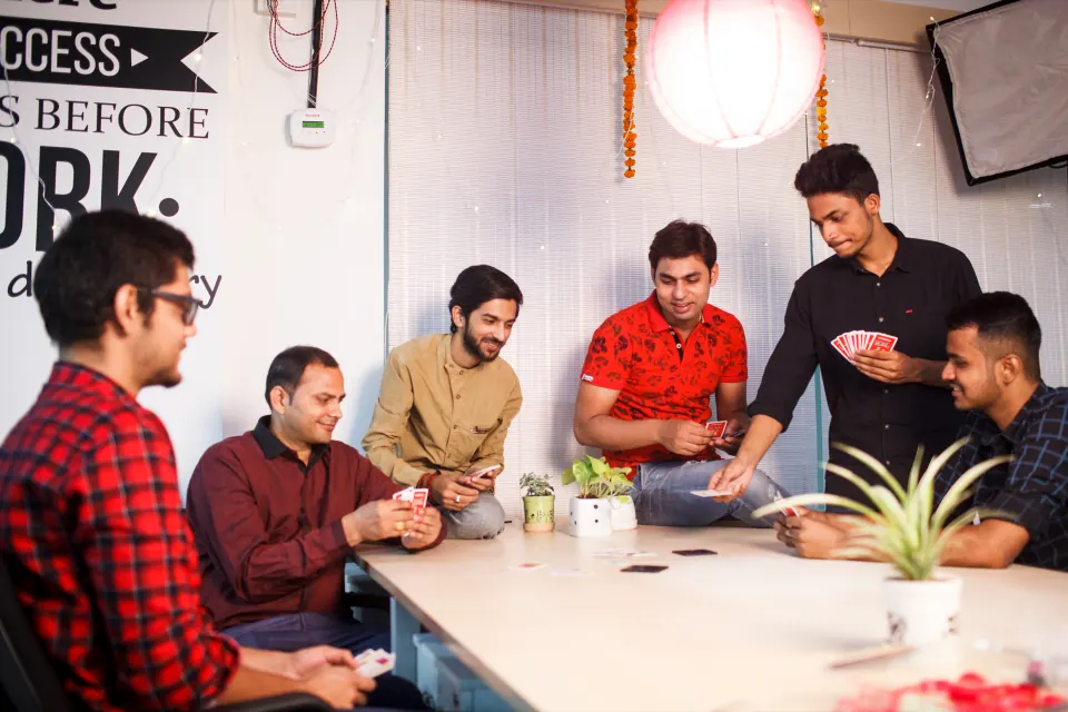 Colleagues playing cards around the office table