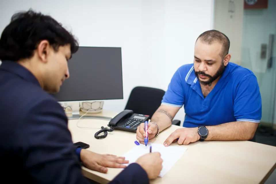 Signing papers at a colleague's desk