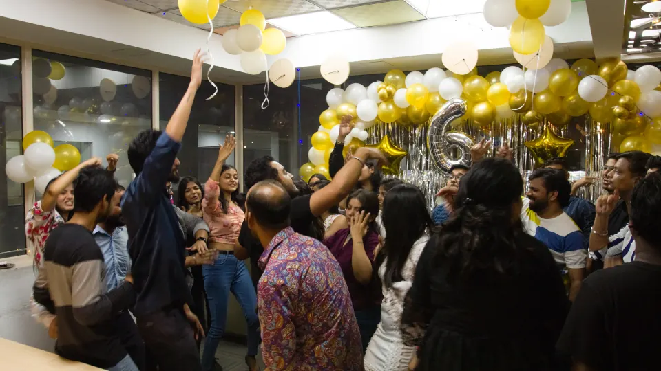Cheering at the office party, under gold and silver balloons