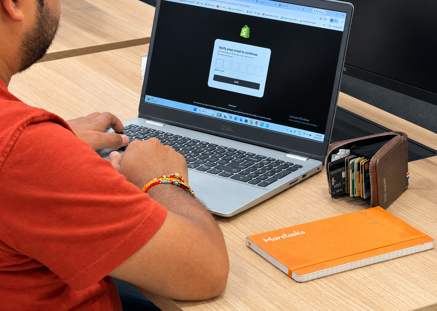 A MoreTasks colleague setting up an online store on a laptop, a MoreTasks notebook beside them