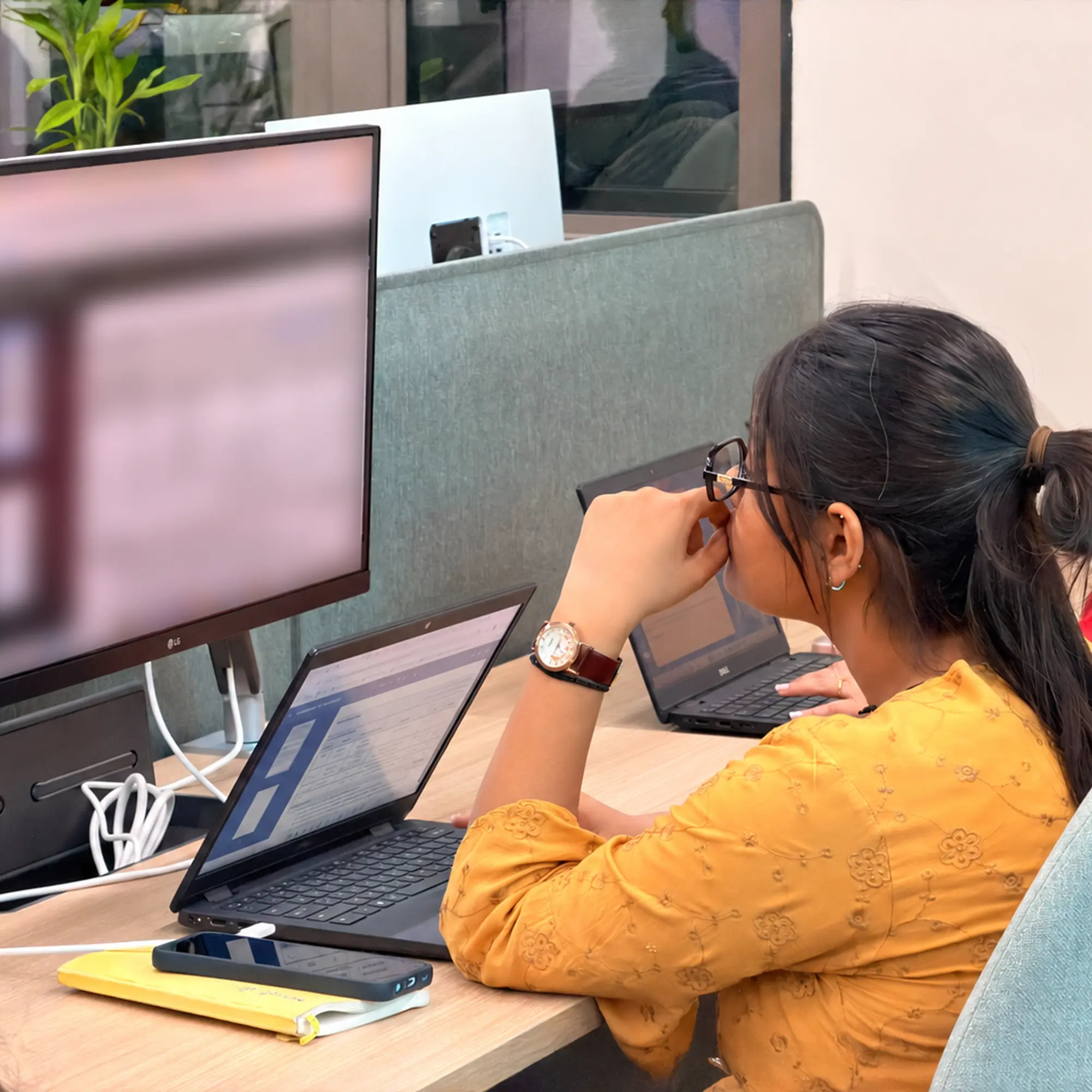 A MoreTasks colleague reviewing content on a laptop at a dual-screen desk