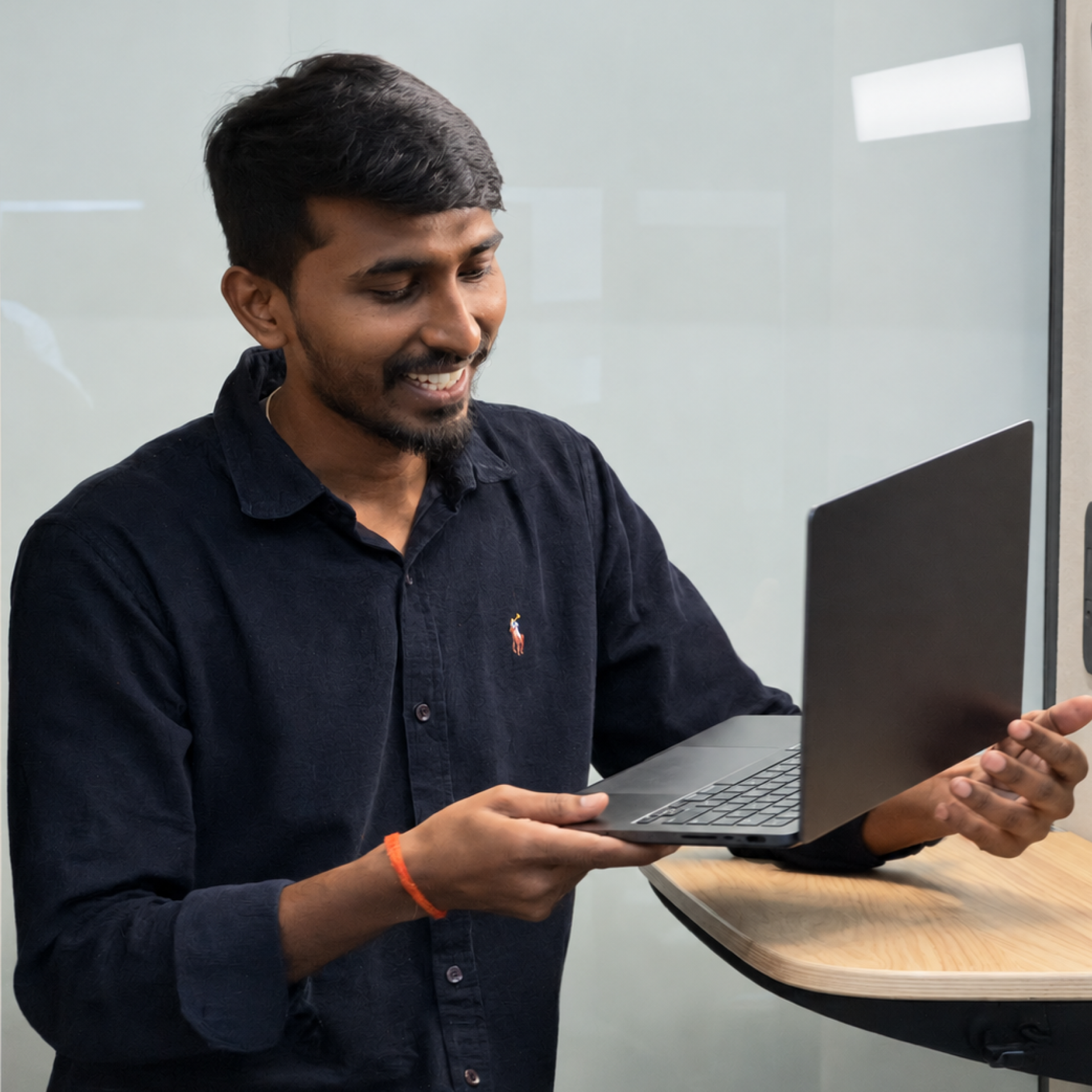 A MoreTasks colleague smiling as he sets a laptop down on a standing desk
